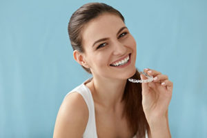 dental braces tx, woman smiling with clear braces in hand