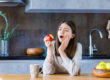 woman holding jaw after biting into apple experiencing common dental problems