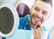 man smiling in mirror after dentist treating a chipped tooth