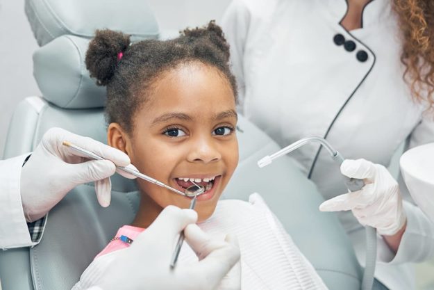 oral health child in dentist chair happy about their oral health